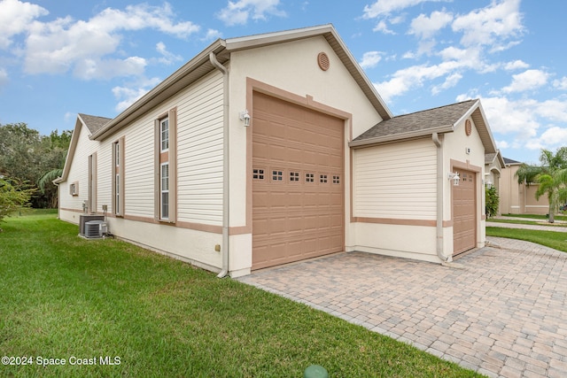 view of side of home with cooling unit, a yard, and a garage