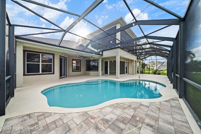 view of swimming pool with glass enclosure, ceiling fan, and a patio area