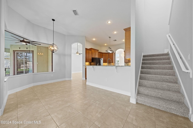 unfurnished living room with ceiling fan with notable chandelier, light tile patterned floors, and sink