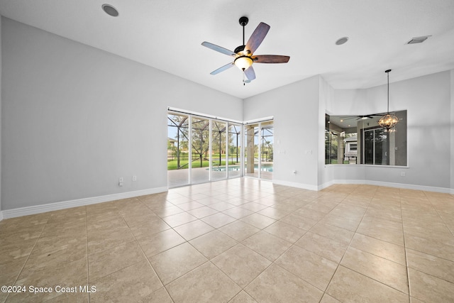 tiled empty room with ceiling fan with notable chandelier