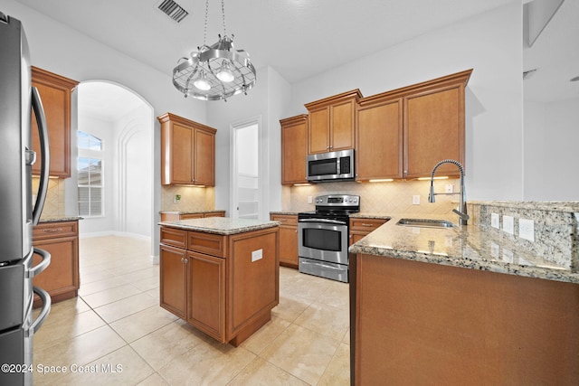 kitchen featuring stainless steel appliances, sink, light tile patterned floors, a chandelier, and hanging light fixtures