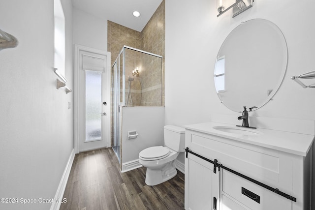 bathroom featuring hardwood / wood-style floors, toilet, a shower with shower door, and a healthy amount of sunlight