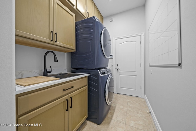 laundry area with cabinets, light tile patterned floors, stacked washer and clothes dryer, and sink