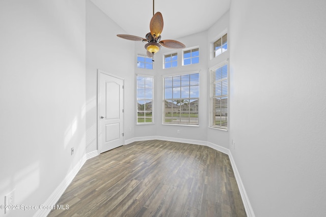 spare room featuring ceiling fan, dark wood-type flooring, and a high ceiling