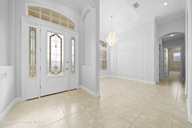 tiled entrance foyer featuring ornamental molding and an inviting chandelier