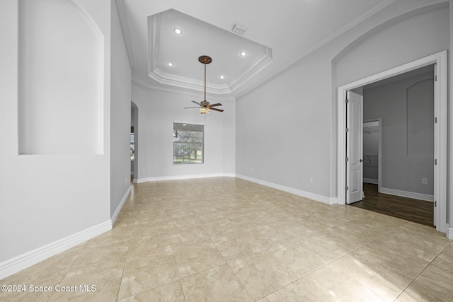 empty room with a tray ceiling, ceiling fan, and ornamental molding