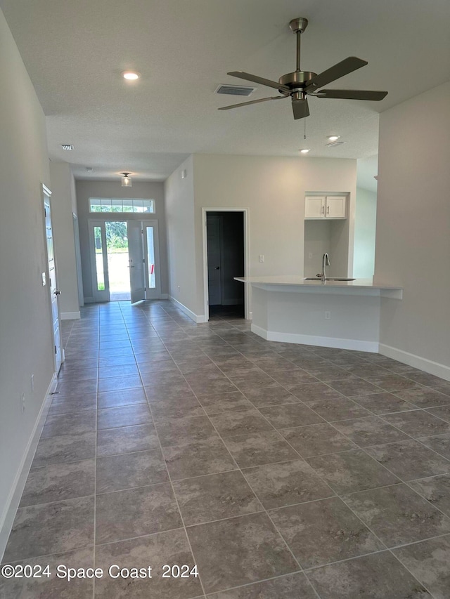 unfurnished living room with dark tile patterned flooring, sink, and ceiling fan