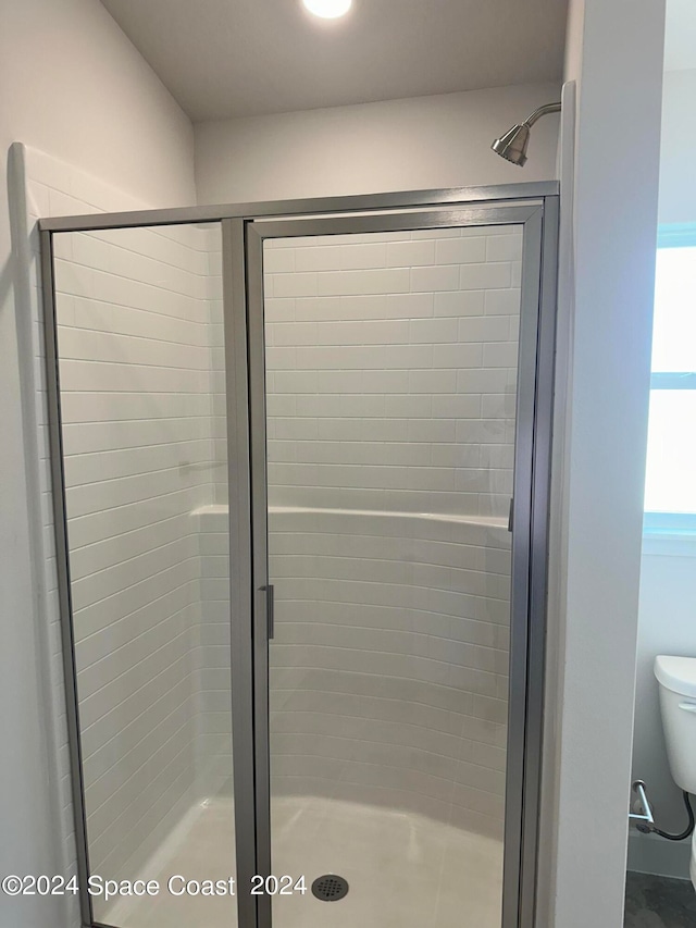 bathroom with toilet and an enclosed shower