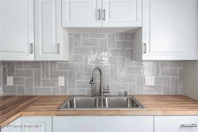 kitchen with white cabinets, sink, backsplash, and butcher block countertops