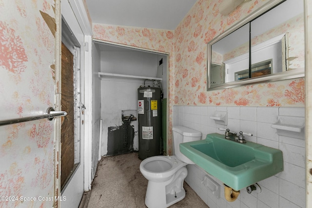 bathroom featuring toilet, electric water heater, sink, and tile walls