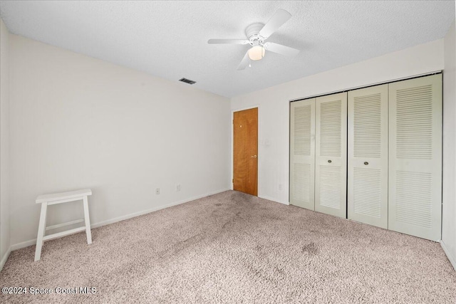 unfurnished bedroom featuring ceiling fan, a closet, carpet, and a textured ceiling