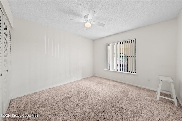 empty room with carpet flooring, a textured ceiling, and ceiling fan