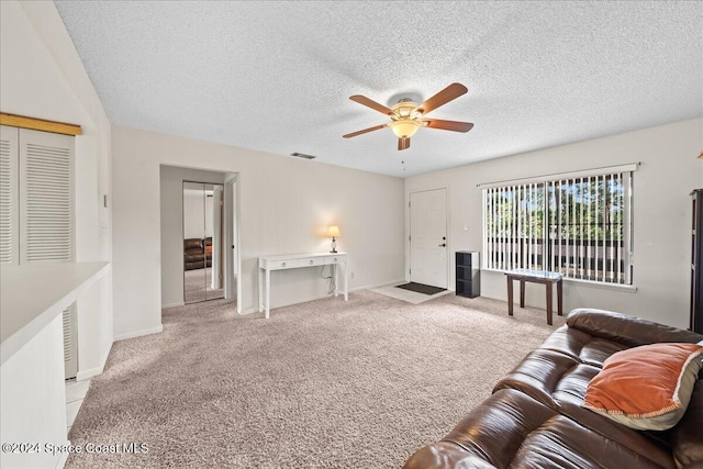 living room with ceiling fan, light colored carpet, and a textured ceiling