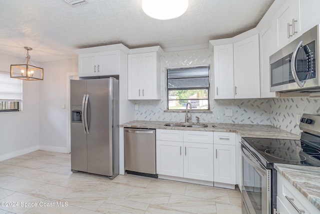 kitchen with hanging light fixtures, sink, light stone countertops, white cabinetry, and appliances with stainless steel finishes