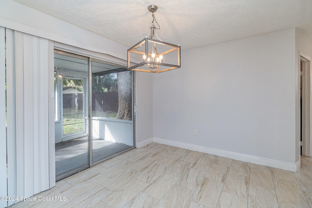 spare room with a notable chandelier and a textured ceiling