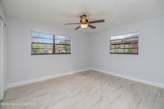 empty room featuring ceiling fan, a healthy amount of sunlight, and a textured ceiling