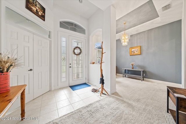 entrance foyer with high vaulted ceiling, light tile patterned flooring, and an inviting chandelier