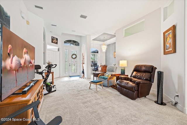 living area with an inviting chandelier and light carpet