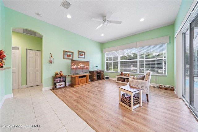 living room featuring ceiling fan, a textured ceiling, and light wood-type flooring