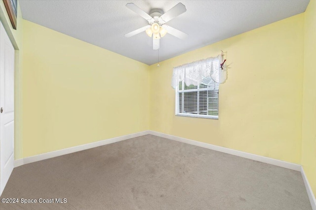 carpeted spare room featuring a textured ceiling and ceiling fan