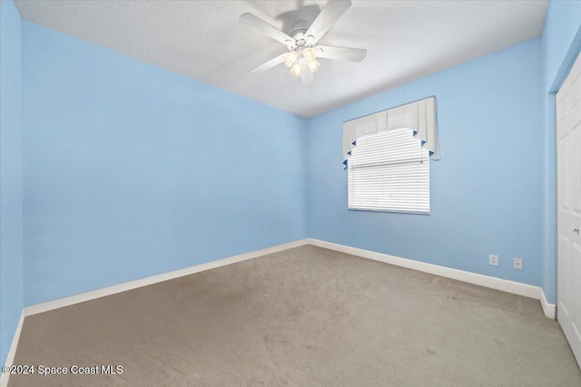 unfurnished room with a textured ceiling, carpet, and ceiling fan