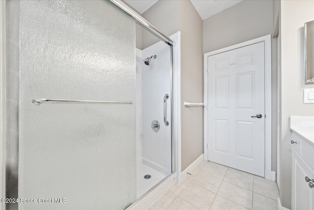 bathroom with walk in shower, vanity, and tile patterned floors