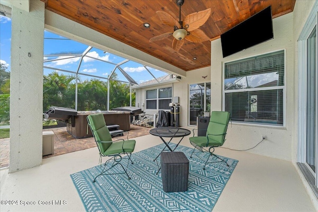 view of patio / terrace featuring ceiling fan, glass enclosure, and a hot tub