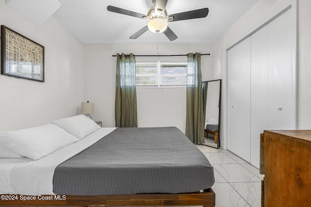 3524 S Atlantic Ave, Cocoa Beach, FL 32931 - bedroom with light marble finish floors, a textured ceiling, a closet, and a ceiling fan