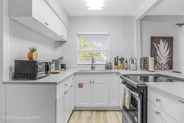 3524 S Atlantic Ave, Cocoa Beach, FL 32931 - kitchen featuring stainless steel electric range, a sink, black microwave, white cabinets, and light wood finished floors