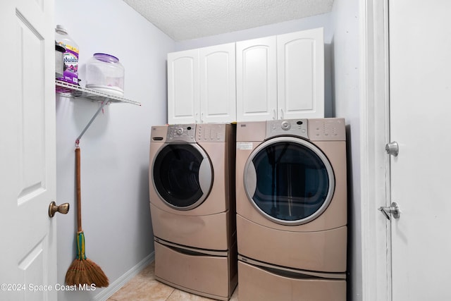 laundry area with washer and clothes dryer, cabinets, light tile patterned floors, and a textured ceiling