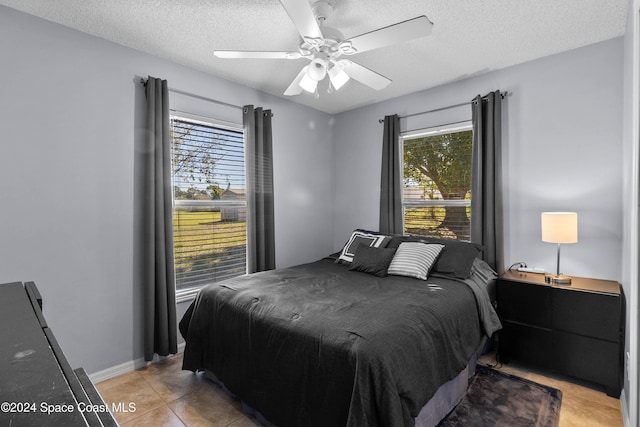 bedroom with ceiling fan, light tile patterned floors, and a textured ceiling