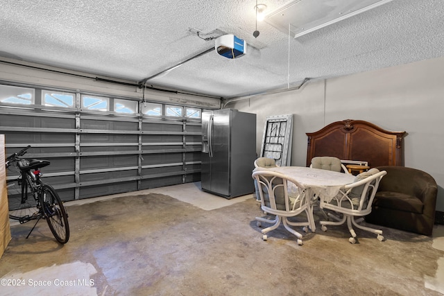 garage with stainless steel refrigerator with ice dispenser and a garage door opener