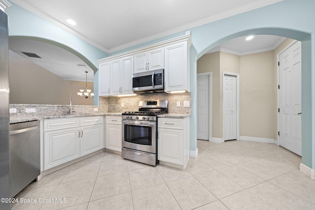 kitchen with white cabinets, appliances with stainless steel finishes, ornamental molding, and sink