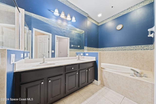 bathroom with a textured ceiling, vanity, a relaxing tiled tub, and tile patterned floors