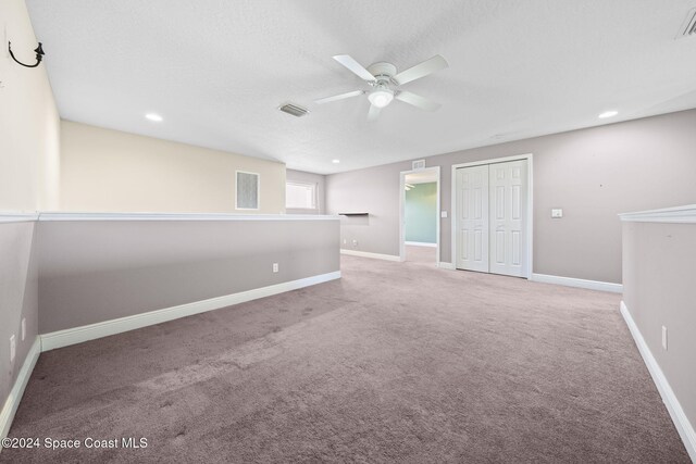 carpeted empty room featuring ceiling fan and a textured ceiling