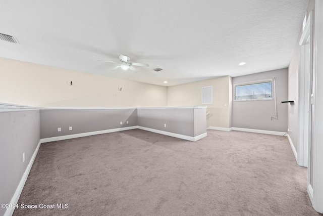 empty room featuring a textured ceiling, ceiling fan, and light carpet