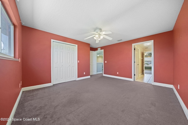 unfurnished bedroom featuring carpet flooring, a textured ceiling, a closet, and ceiling fan