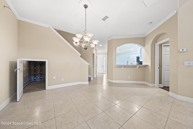 spare room featuring ornamental molding, light tile patterned floors, and an inviting chandelier