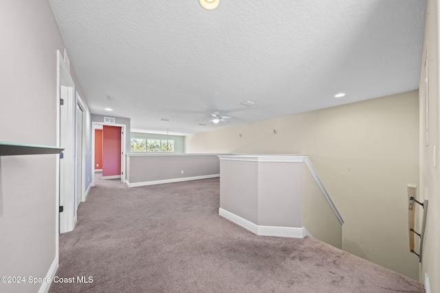 spare room featuring carpet flooring, ceiling fan, and a textured ceiling