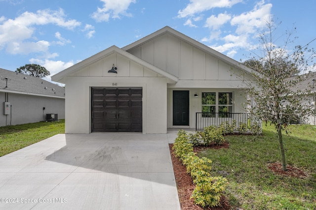 view of front of property featuring a front yard, central AC unit, and a garage