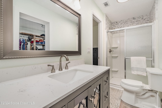 bathroom with hardwood / wood-style floors, an enclosed shower, vanity, and toilet