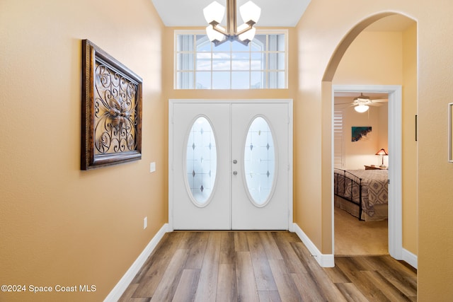 foyer entrance featuring french doors, ceiling fan with notable chandelier, and hardwood / wood-style flooring