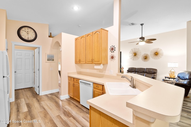 kitchen with white appliances, sink, light wood-type flooring, and kitchen peninsula