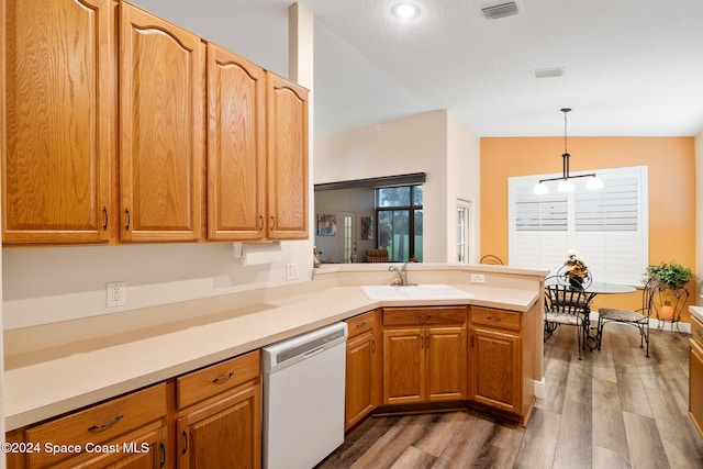 kitchen featuring decorative light fixtures, vaulted ceiling, sink, dishwasher, and kitchen peninsula