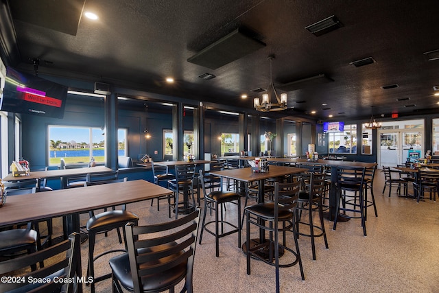 bar featuring french doors, a notable chandelier, and a textured ceiling