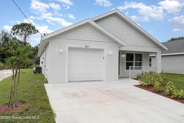 view of front of home featuring a front yard, a garage, covered porch, and central AC unit