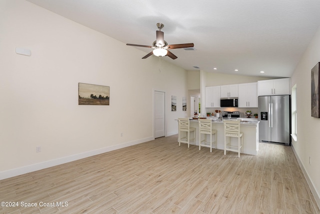 kitchen featuring appliances with stainless steel finishes, white cabinets, light hardwood / wood-style floors, and an island with sink