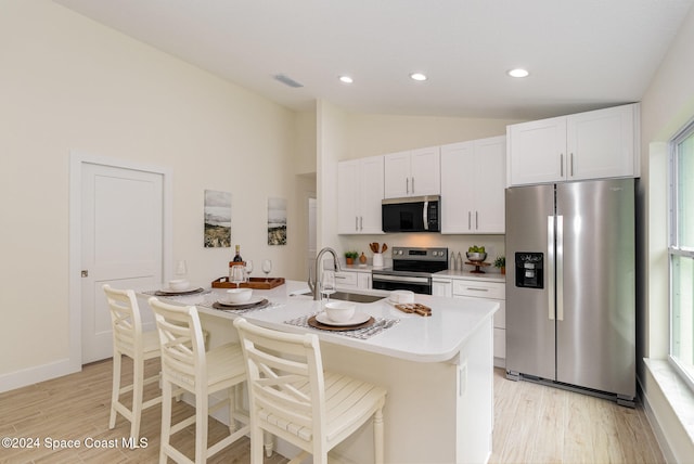 kitchen featuring appliances with stainless steel finishes, sink, an island with sink, white cabinets, and a breakfast bar