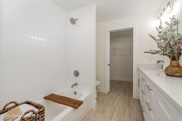 full bathroom with vanity, toilet, tiled shower / bath, and hardwood / wood-style floors