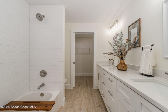 full bathroom featuring vanity, tiled shower / bath combo, wood-type flooring, and toilet